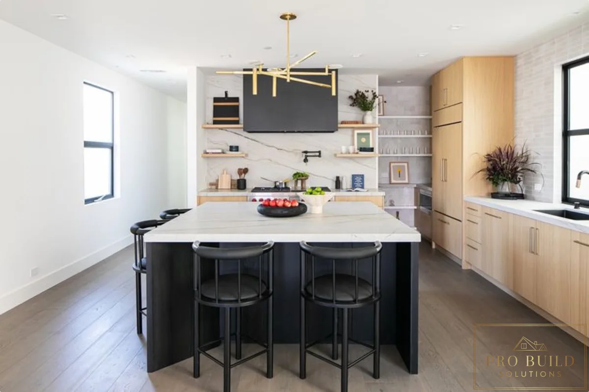Contemporary kitchen design featuring pale wood cabinetry, oversized island, marble-style backsplash, and minimalist black accents, Wilmette, IL