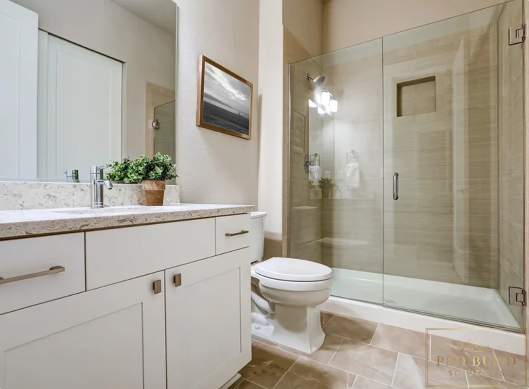 Clean transitional bathroom design featuring a custom white vanity, walk-in glass shower, and soft beige stone-look tile, Wheaton