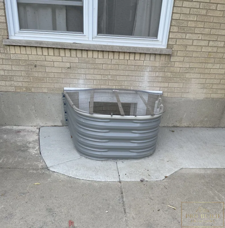 Basement window well upgrade featuring corrugated metal well, clear cover, and masonry wall detail, Elmhurst