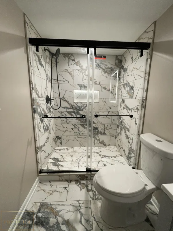 Modern bathroom renovation featuring marble-style tile shower, glass enclosure, and black hardware accents, Itasca