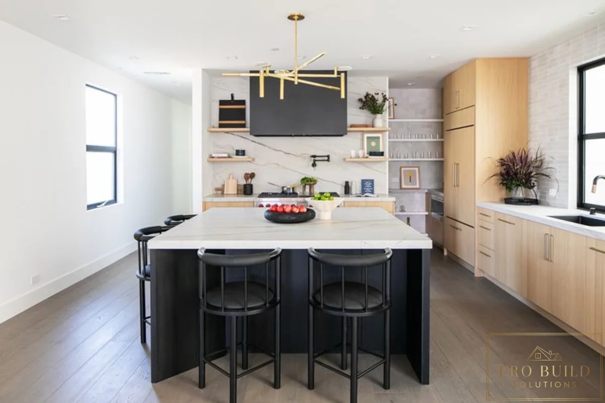 Contemporary kitchen design featuring pale wood cabinetry, oversized island, marble-style backsplash, and minimalist black accents, Wilmette, IL