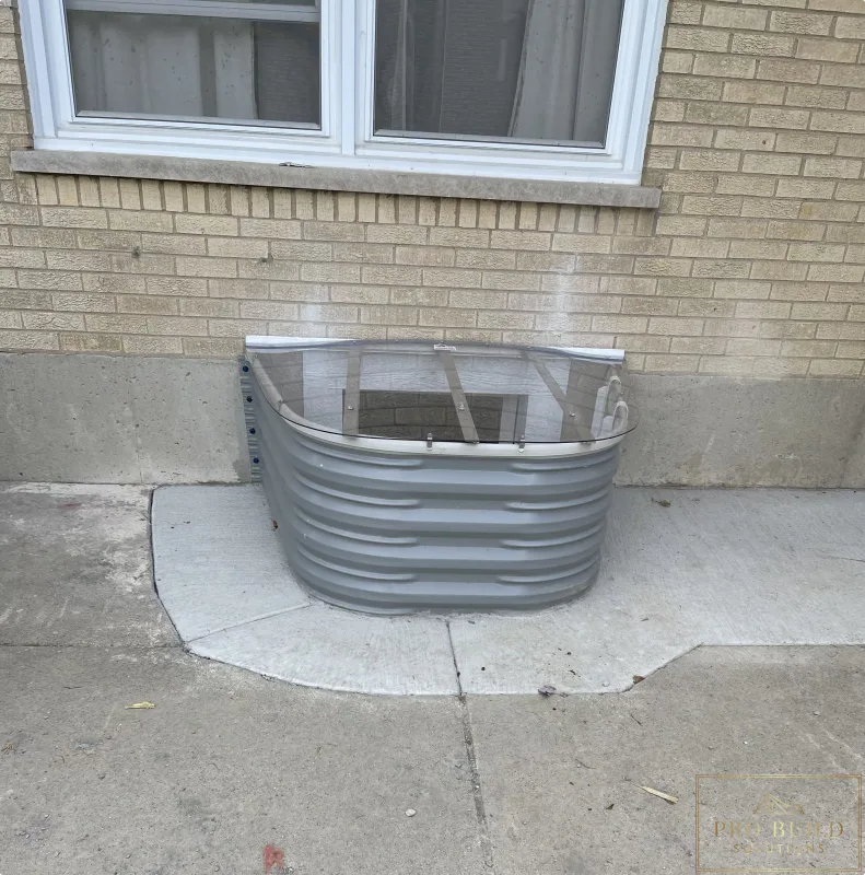 Basement window well upgrade featuring corrugated metal well, clear cover, and masonry wall detail, Elmhurst