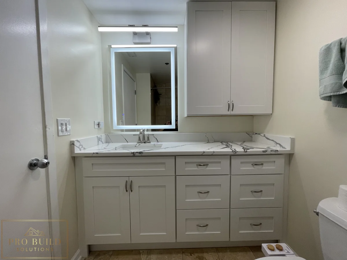 Small bathroom renovation featuring custom white vanity cabinets, marble-style counter, and updated mirror lighting, Lisle, IL