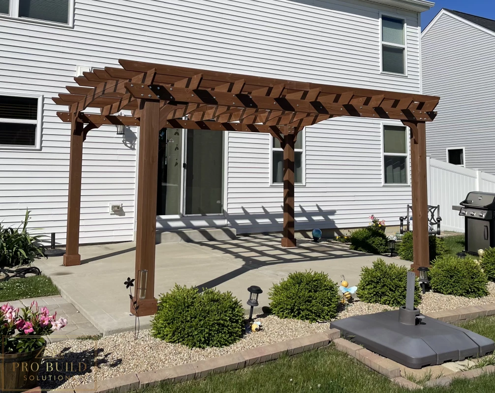 Custom wood pergola over backyard concrete patio with decorative rafters and posts, Joliet, IL