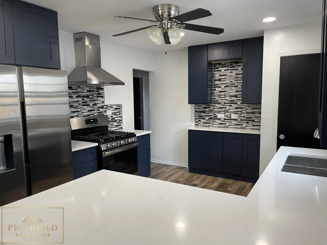 Residential kitchen renovation with navy cabinetry, quartz counters, wood-look flooring, and updated appliances, La Grange, IL