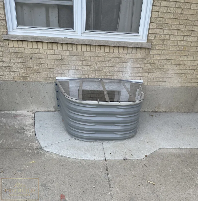 Basement window well upgrade featuring corrugated metal well, clear cover, and masonry wall detail, Elmhurst