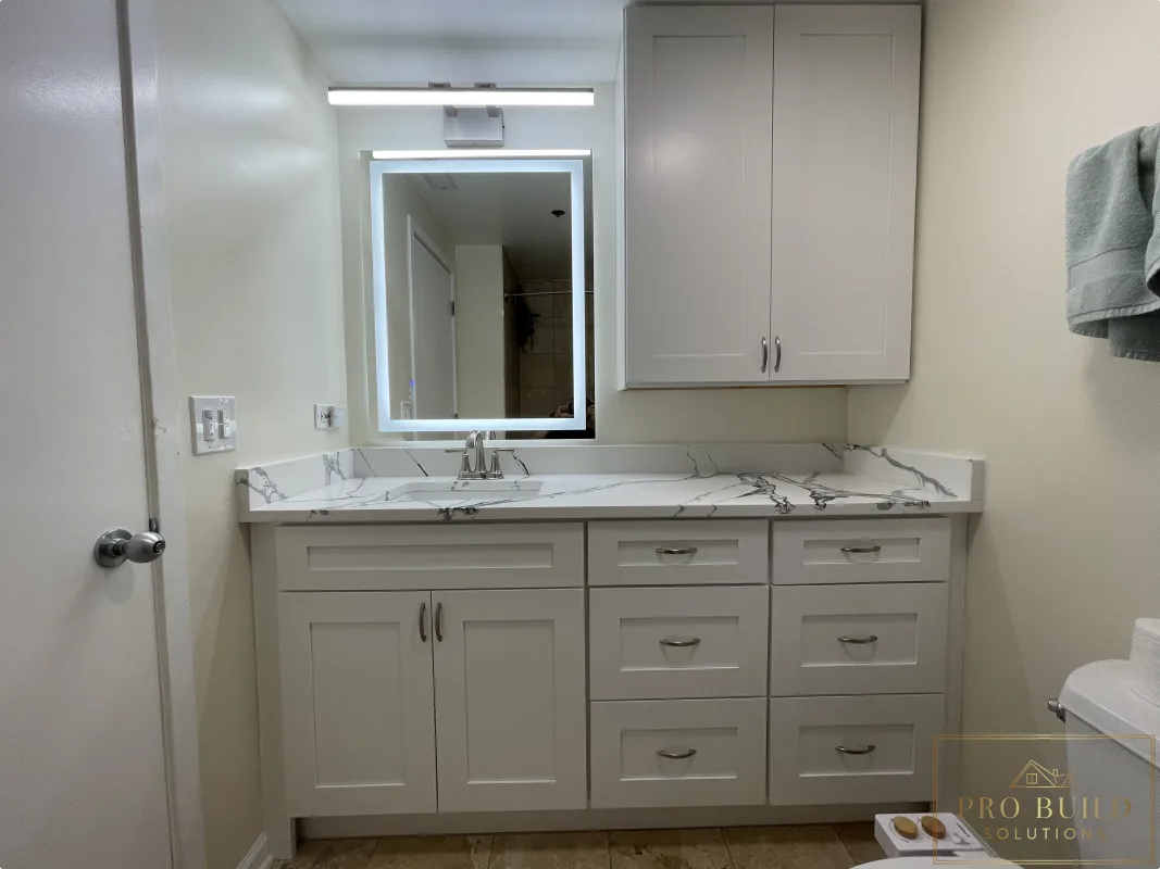 Updated bathroom vanity remodel with shaker cabinetry, stone-look countertop, wall storage, and modern illuminated mirror., Lisle