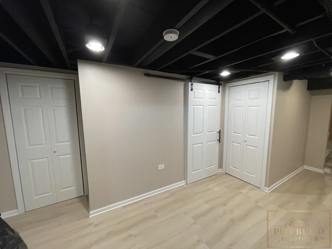 Basement remodel with black exposed ceiling, light wood-look flooring, white doors, and recessed lighting, Glen Ellyn