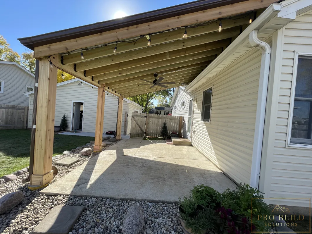 Shaded backyard patio cover built with wood posts, exposed beams, and metal roofing, Rolling Meadows
