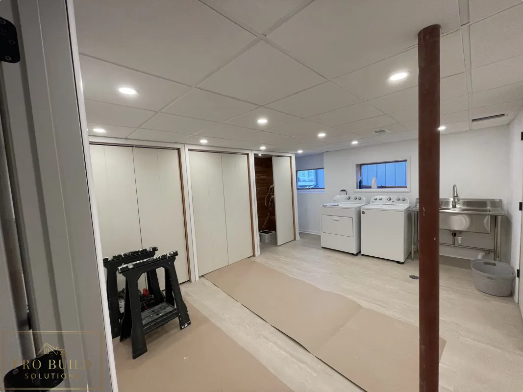 Basement finishing project with laundry space, recessed ceiling lights, closet doors, and durable plank flooring before Final Paint, Western Springs