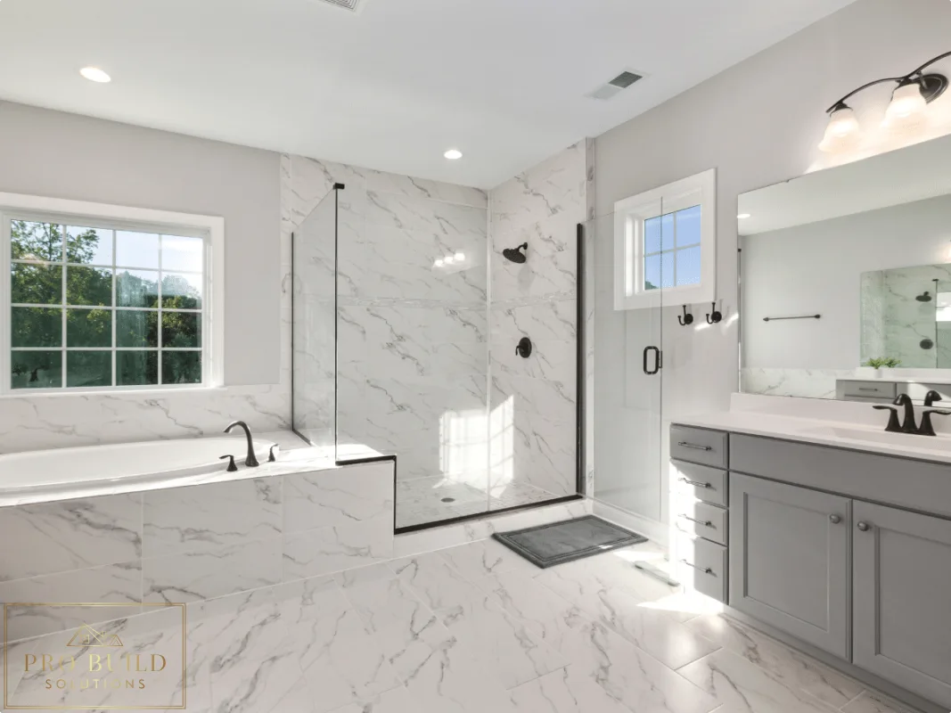 Bright spa-style bathroom featuring marble-look surfaces, frameless shower enclosure, built-in tub, and soft gray cabinetry, Glen Ellyn