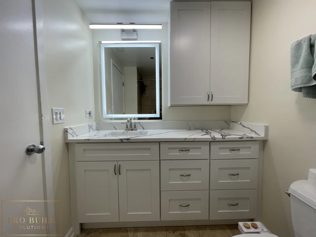 Small bathroom renovation featuring custom white vanity cabinets, marble-style counter, and updated mirror lighting, Lisle, IL