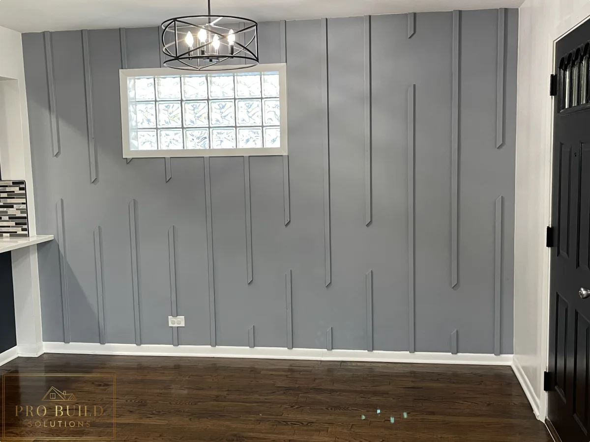 Interior trim feature wall with gray painted battens, modern chandelier, and dark wood flooring, Western Springs, IL