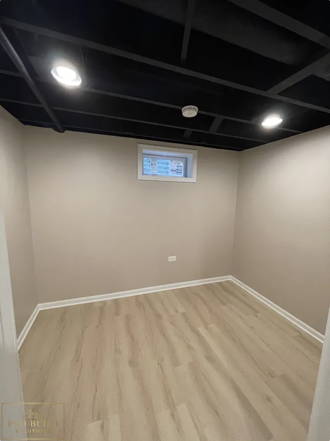 Small basement finishing project with black ceiling, bright recessed lights, and clean white trim, Bartlett