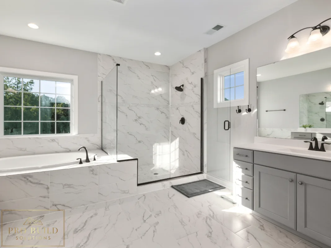 Bright spa-style bathroom featuring marble-look surfaces, frameless shower enclosure, built-in tub, and soft gray cabinetry, Glen Ellyn