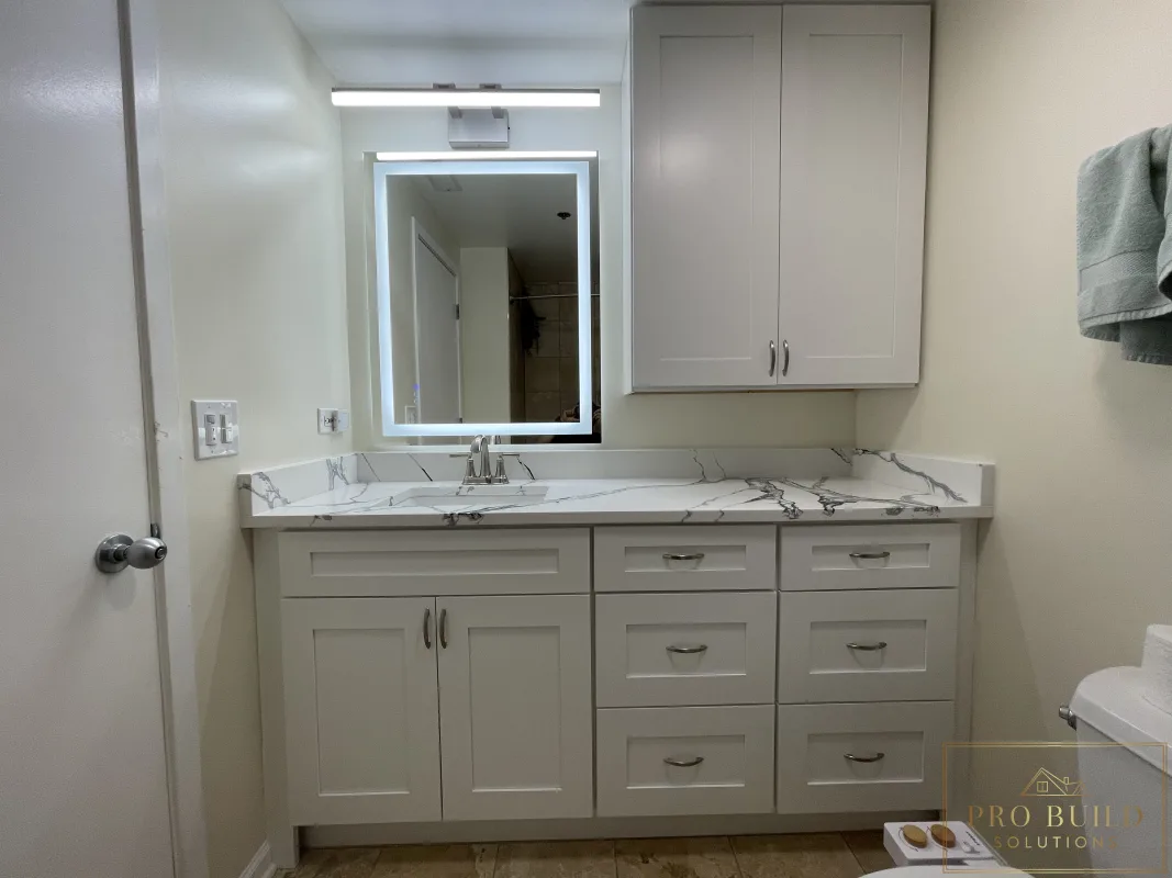 Updated bathroom vanity remodel with shaker cabinetry, stone-look countertop, wall storage, and modern illuminated mirror, Lisle