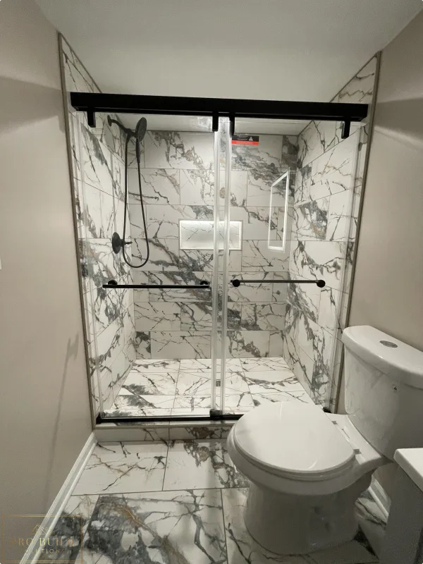Modern bathroom renovation featuring marble-style tile shower, glass enclosure, and black hardware accents, Itasca