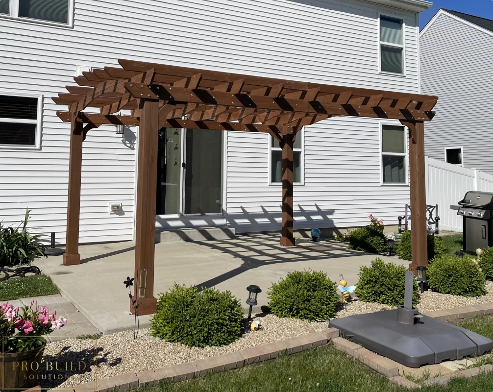 Custom wood pergola over backyard concrete patio with decorative rafters and posts, Joliet, IL