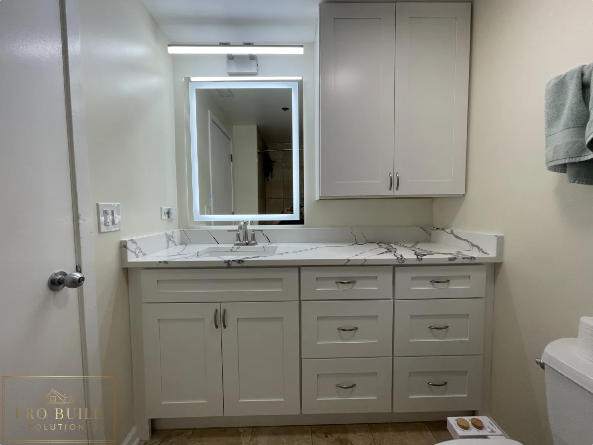 Small bathroom renovation featuring custom white vanity cabinets, marble-style counter, and updated mirror lighting, Lisle, IL