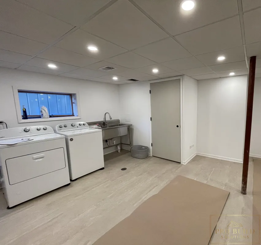 Views of the New Storage Door in the Basement finishing project with laundry space, recessed ceiling lights, closet doors, and durable plank flooring before Final Paint, Western Springs