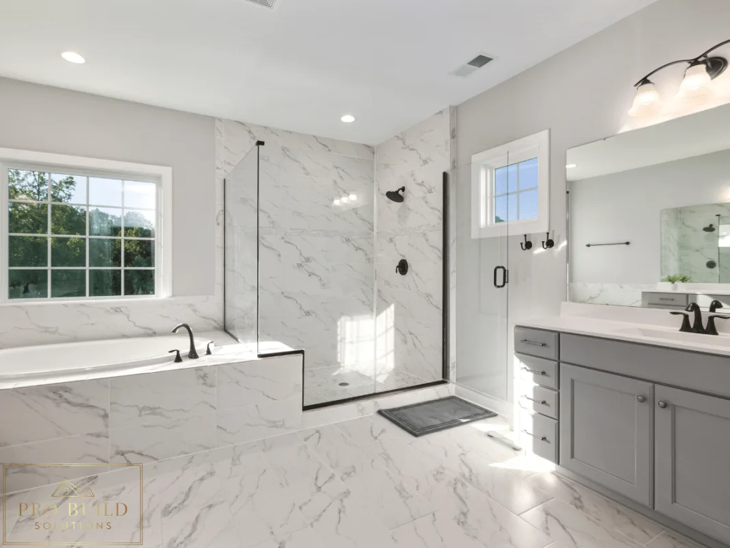 Bright spa-style bathroom featuring marble-look surfaces, frameless shower enclosure, built-in tub, and soft gray cabinetry, Glen Ellyn