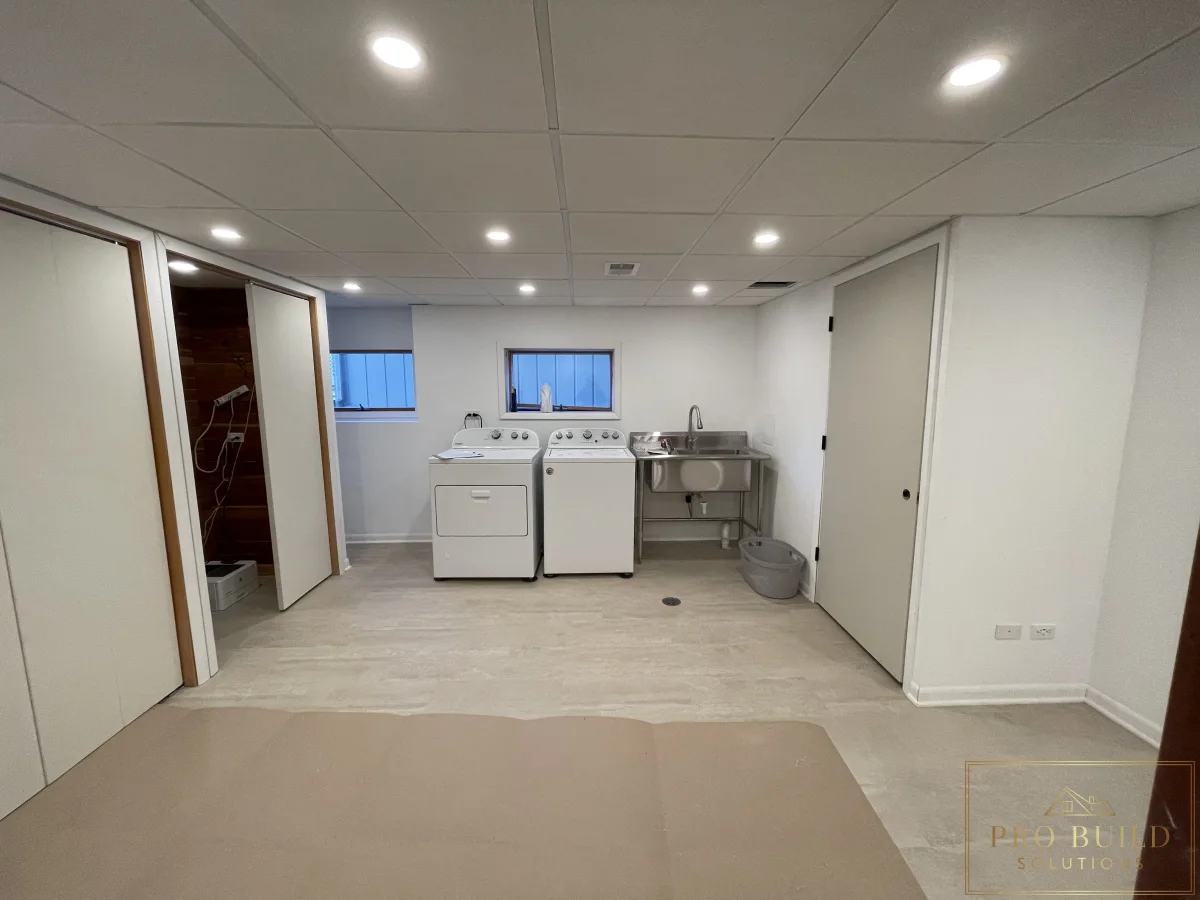 Basement renovation featuring washer and dryer hookups, drop ceiling, utility sink, and clean finished walls, Western Springs
