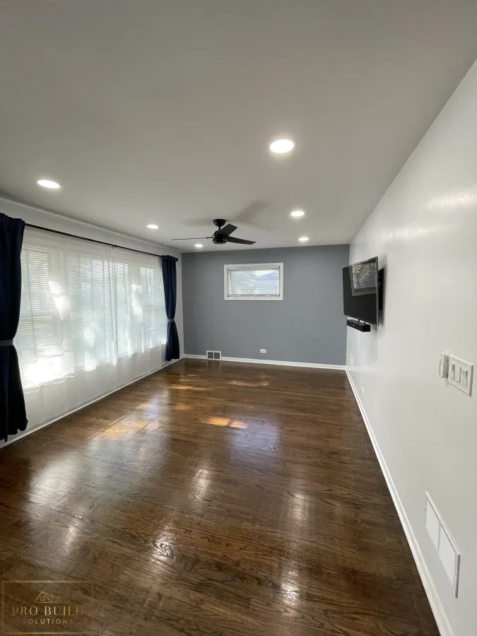 Residential interior renovation featuring polished wood floors, fresh paint, recessed lighting, and mounted TV setup, Western Springs, IL