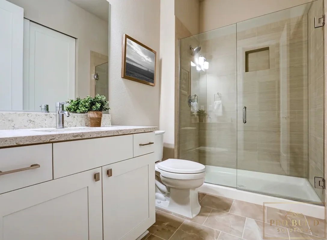 Clean transitional bathroom design featuring a custom white vanity, walk-in glass shower, and soft beige stone-look tile, Wheaton