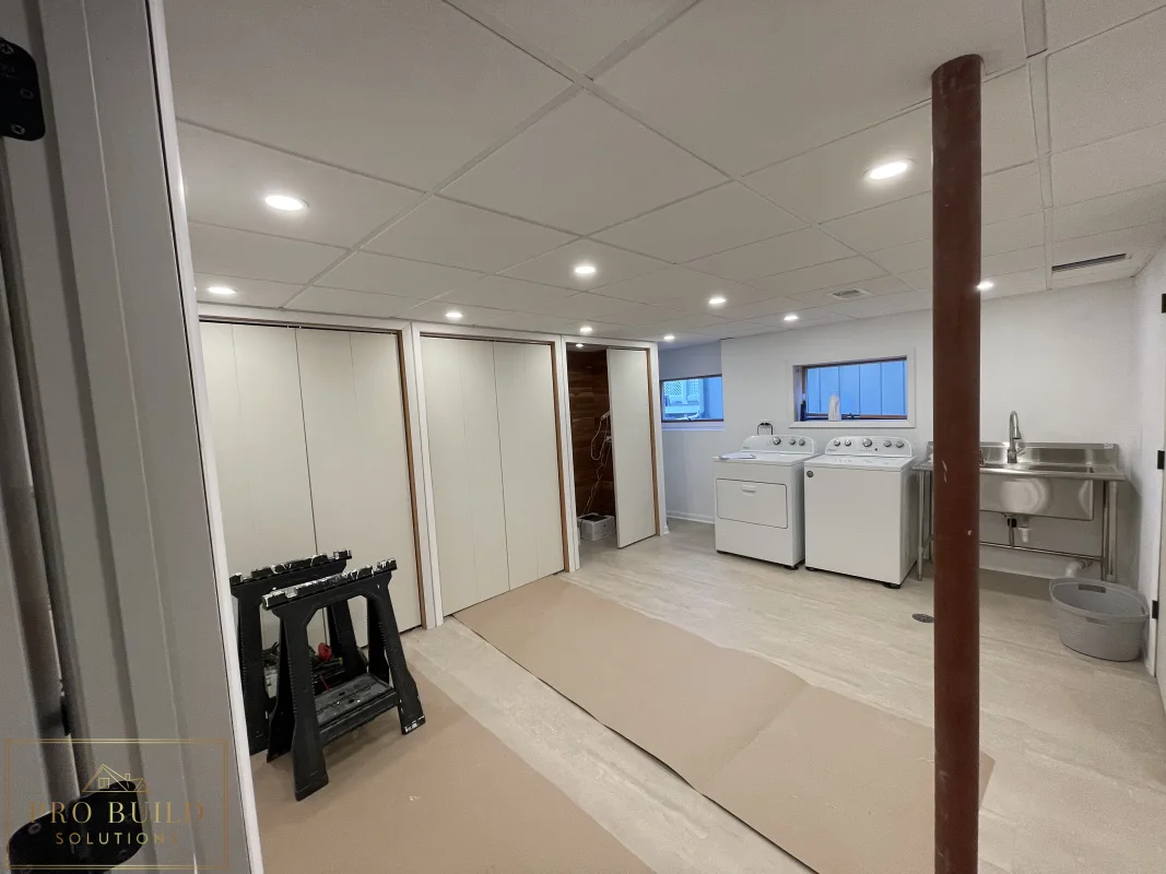 Basement finishing project with laundry space, recessed ceiling lights, closet doors, and durable plank flooring before Final Paint, Western Springs