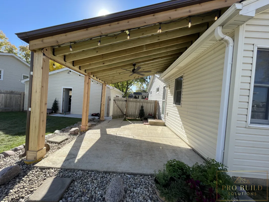 Shaded backyard patio cover built with wood posts, exposed beams, and metal roofing, Rolling Meadows