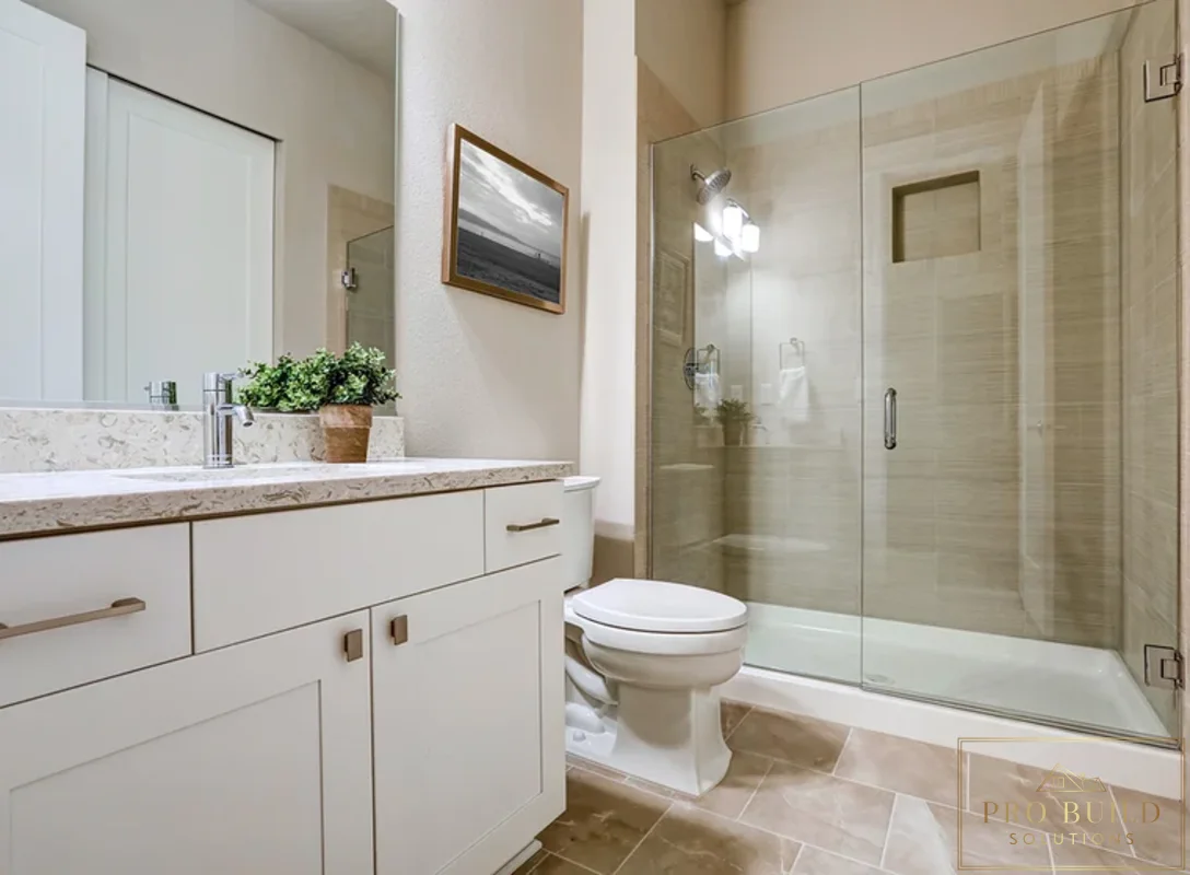 Clean transitional bathroom design featuring a custom white vanity, walk-in glass shower, and soft beige stone-look tile, Wheaton